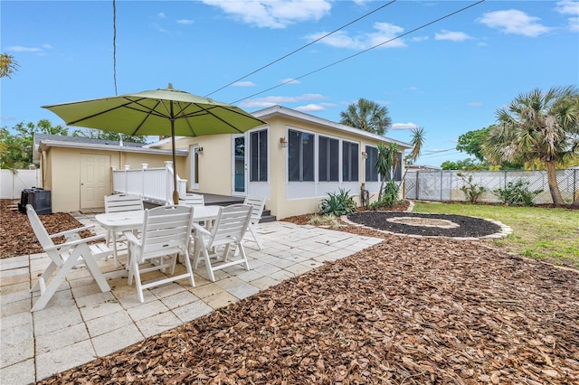 exterior space featuring a sunroom, outdoor dining area, and fence