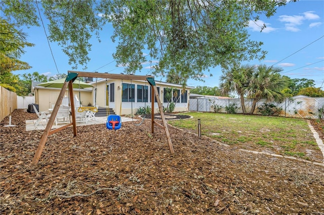 rear view of house featuring a lawn, a sunroom, and a fenced backyard
