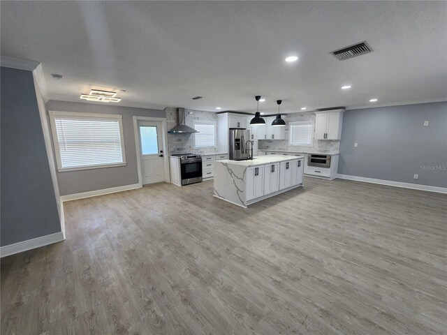4619 Helena St NE, Saint Petersburg, FL 33703 - kitchen featuring tasteful backsplash, ornamental molding, visible vents, appliances with stainless steel finishes, and wall chimney exhaust hood