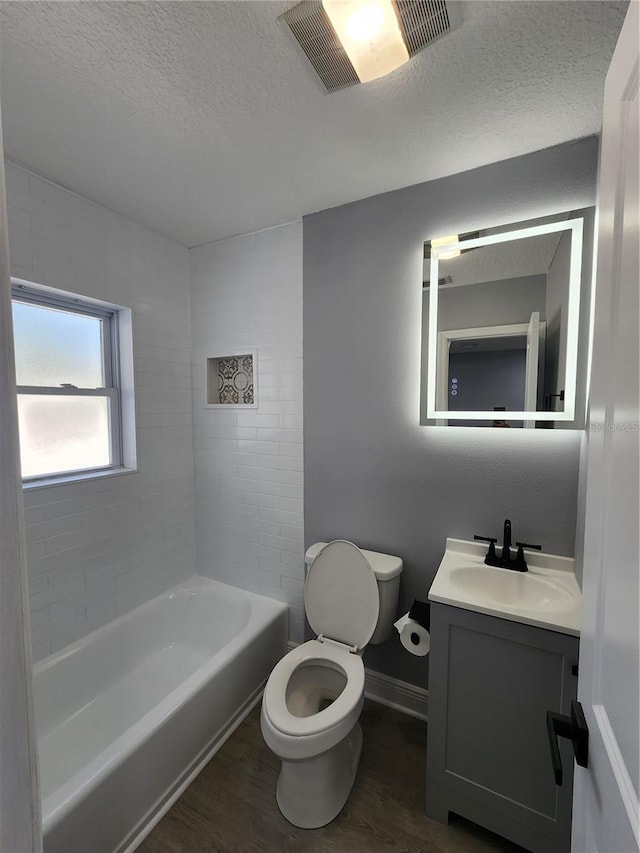 4619 Helena St NE, Saint Petersburg, FL 33703 - bathroom with toilet, a tub, wood finished floors, a textured ceiling, and visible vents