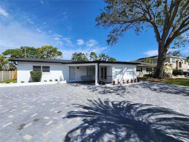 4619 Helena St NE, Saint Petersburg, FL 33703 - view of front of house featuring fence, decorative driveway, stucco siding, and a porch