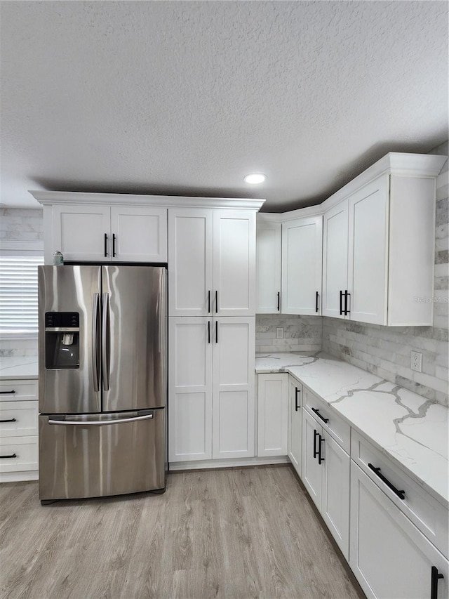 4619 Helena St NE, Saint Petersburg, FL 33703 - kitchen featuring white cabinetry, stainless steel fridge with ice dispenser, light stone counters, and light wood finished floors