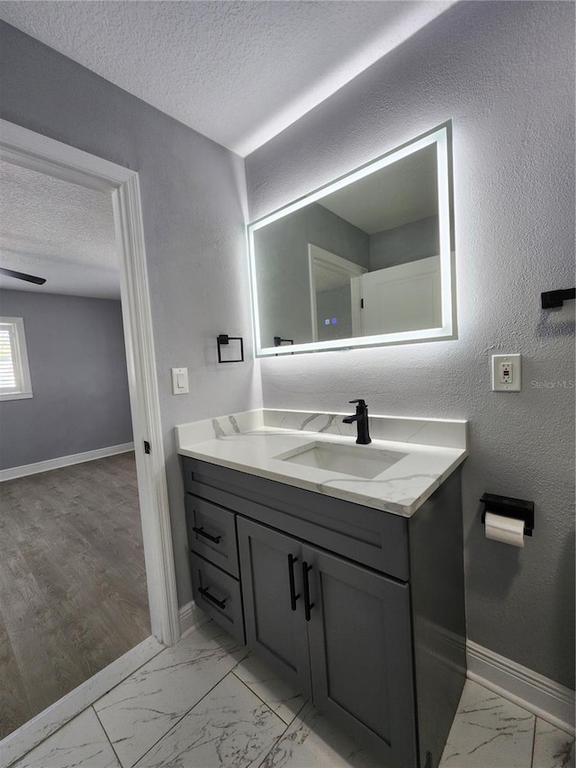 4619 Helena St NE, Saint Petersburg, FL 33703 - bathroom featuring a textured ceiling, baseboards, marble finish floor, vanity, and a textured wall