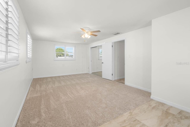 spare room with carpet, visible vents, baseboards, and ceiling fan
