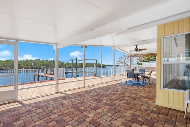 unfurnished sunroom with a water view, outdoor dining area, and a ceiling fan