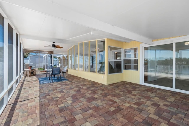 unfurnished sunroom featuring outdoor dining area and a ceiling fan