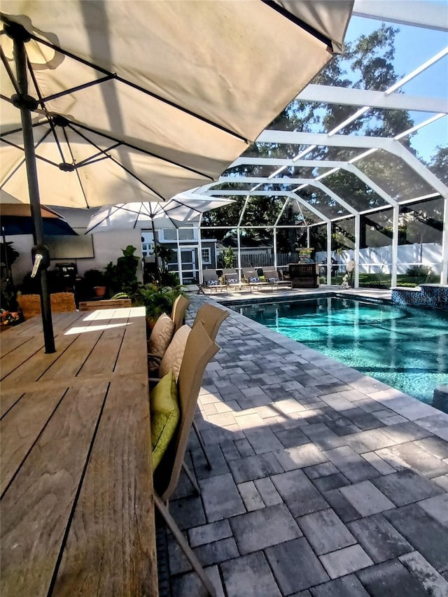 outdoor pool featuring a patio, a fenced backyard, an outdoor structure, and glass enclosure