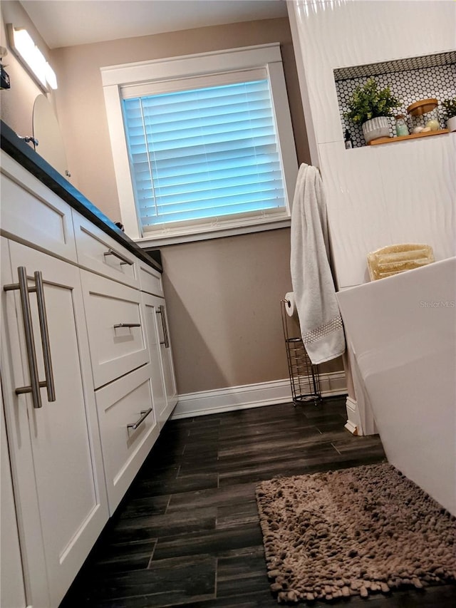 full bathroom with a freestanding bath, baseboards, and wood finished floors