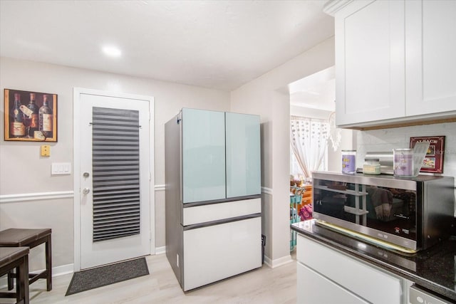 5050 68th Way N, Saint Petersburg, FL 33709 - kitchen featuring baseboards, light wood-style flooring, stainless steel microwave, and white cabinets