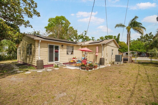 5050 68th Way N, Saint Petersburg, FL 33709 - rear view of property with central air condition unit, roof mounted solar panels, fence, and a lawn