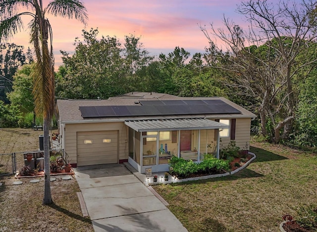 5050 68th Way N, Saint Petersburg, FL 33709 - view of front of house featuring an attached garage, driveway, a sunroom, and solar panels