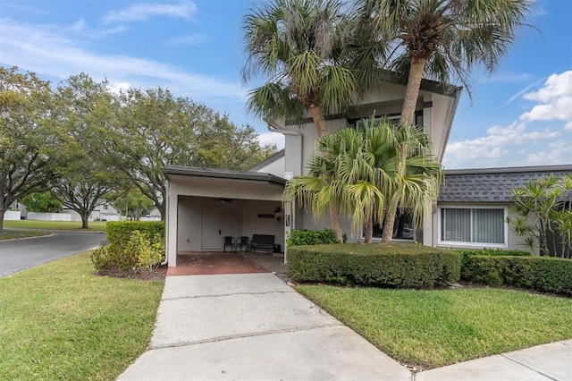 view of front of home with a carport, a ceiling fan, driveway, and a front yard
