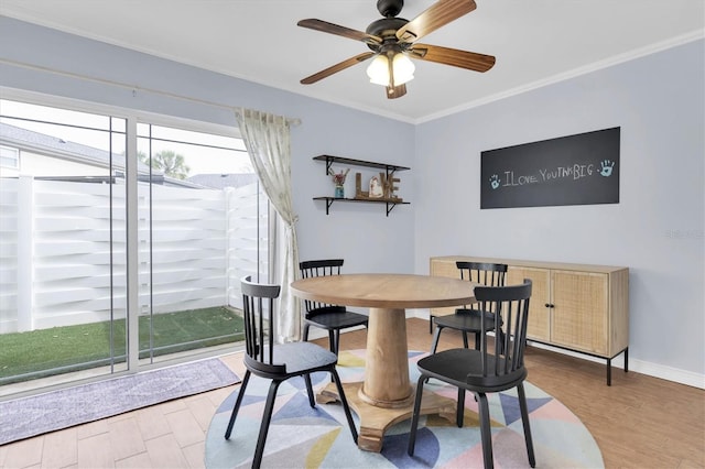 dining room featuring crown molding, wood finished floors, a ceiling fan, and baseboards