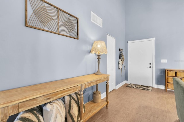 foyer entrance featuring baseboards, visible vents, and a high ceiling