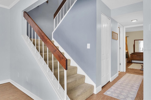stairs featuring baseboards, wood finished floors, and crown molding