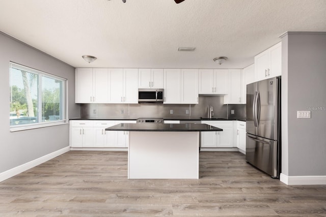 8555 112th St Unit 209, Seminole, FL 33772 - kitchen featuring a sink, a kitchen island, appliances with stainless steel finishes, visible vents, and white cabinets