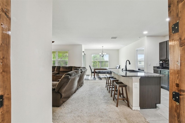 6882 Silverado Ranch Blvd, Zephyrhills, FL 33541 - kitchen with an island with sink, a breakfast bar, a sink, a chandelier, and open floor plan