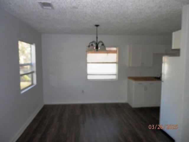 851 Easy St, Brooksville, FL 34601 - unfurnished dining area with an inviting chandelier, baseboards, dark wood finished floors, a textured ceiling, and visible vents