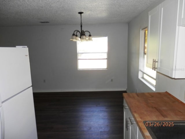 851 Easy St, Brooksville, FL 34601 - unfurnished dining area with a notable chandelier, a textured ceiling, baseboards, and dark wood finished floors