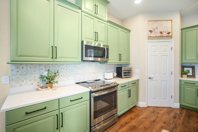 kitchen with appliances with stainless steel finishes, tasteful backsplash, dark wood finished floors, light countertops, and green cabinetry