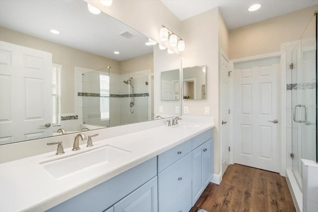 bathroom with wood finished floors, a sink, and a stall shower