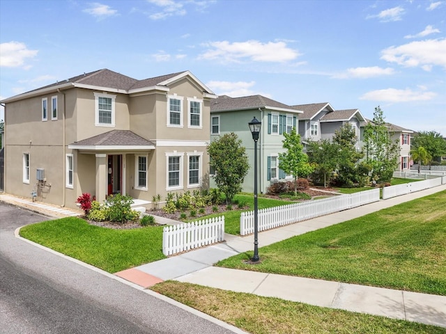 traditional-style house featuring fence, a residential view, a front yard, and stucco siding
