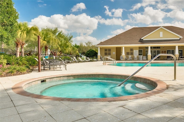 community pool with a patio, a hot tub, and fence