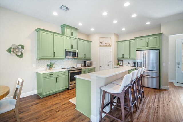 11109 Great Neck Rd, Riverview, FL 33578 - kitchen with appliances with stainless steel finishes, green cabinetry, backsplash, dark wood-type flooring, and recessed lighting