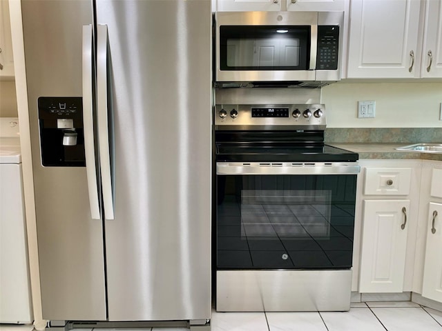 1655 S Highland Ave Unit I286, Clearwater, FL 33756 - kitchen featuring appliances with stainless steel finishes, light tile patterned floors, white cabinets, washer / clothes dryer, and a sink