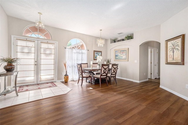 dining room featuring arched walkways, baseboards, wood finished floors, and a chandelier