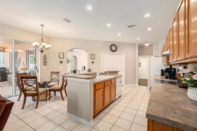 kitchen with dishwasher, a kitchen island with sink, arched walkways, light tile patterned floors, and visible vents