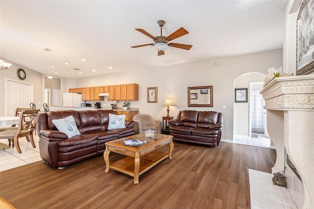 living area featuring a ceiling fan, arched walkways, light wood-type flooring, baseboards, and recessed lighting