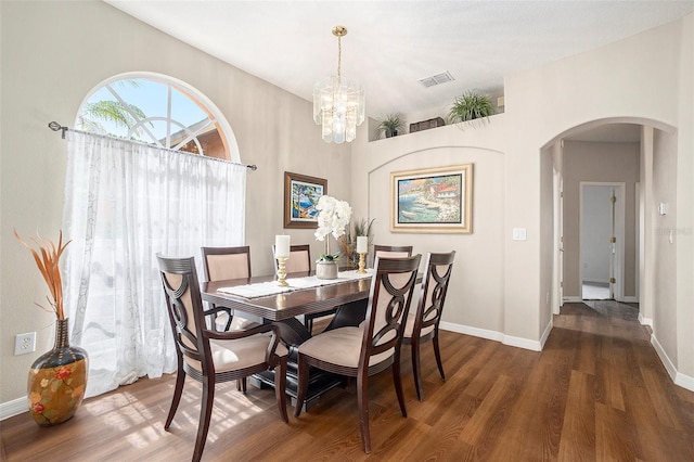 dining room featuring arched walkways, visible vents, a chandelier, and wood finished floors