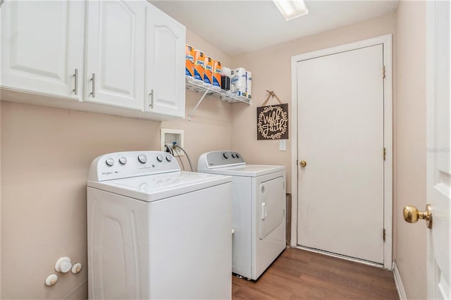 washroom featuring light wood-style floors, washer and clothes dryer, and cabinet space