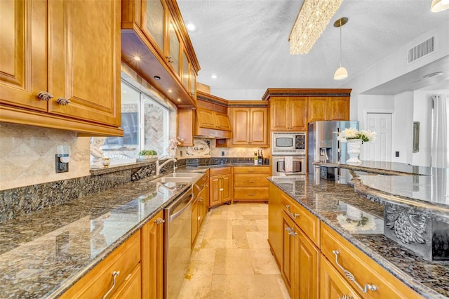13122 Prestwick Dr, Riverview, FL 33579 - kitchen featuring dark stone counters, visible vents, a sink, stainless steel appliances, and brown cabinets