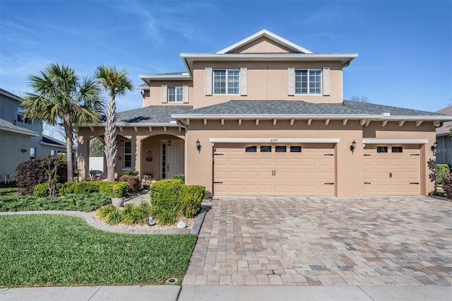 view of front of house with decorative driveway, stucco siding, and an attached garage