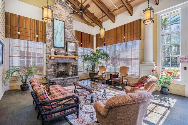 8247 Westhaven Dr, Land O Lakes, FL 34638 - living room with high vaulted ceiling, stone tile flooring, ornate columns, an outdoor stone fireplace, and a ceiling fan