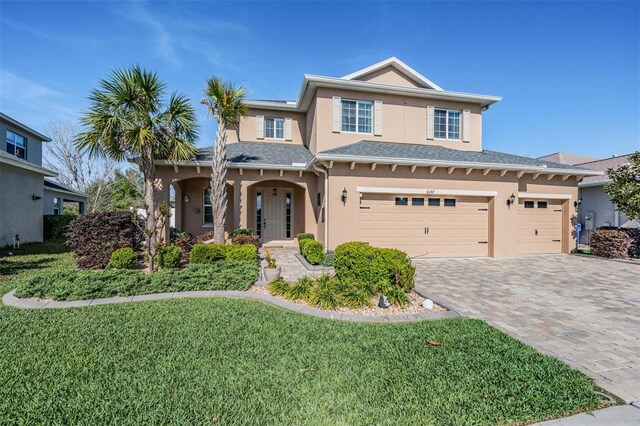 8247 Westhaven Dr, Land O Lakes, FL 34638 - traditional home featuring stucco siding, decorative driveway, a front yard, and an attached garage