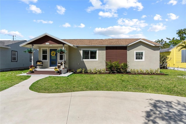 view of front of home with roof with shingles, a front yard, a porch, and stucco siding