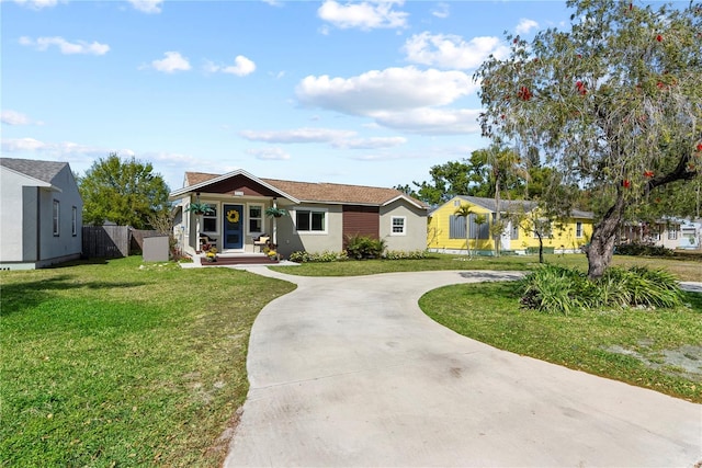 ranch-style home featuring stucco siding, curved driveway, a front yard, fence, and covered porch