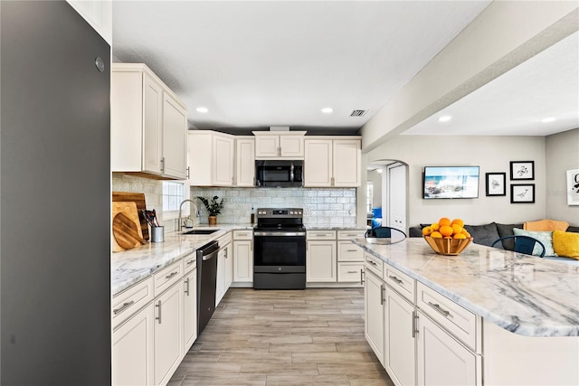 kitchen featuring tasteful backsplash, light stone countertops, stainless steel appliances, arched walkways, and a sink