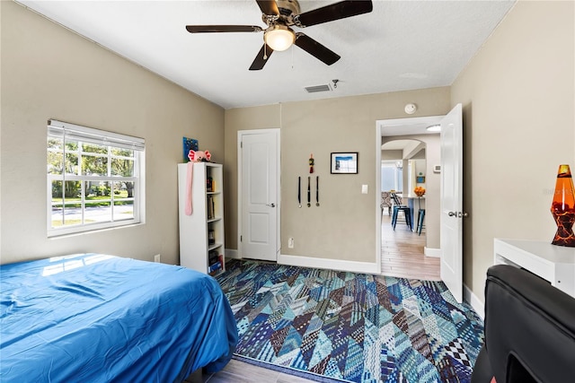 bedroom with visible vents, baseboards, arched walkways, and ceiling fan