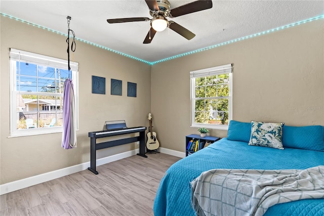 bedroom featuring a textured ceiling, wood finished floors, baseboards, and a ceiling fan