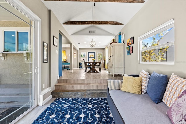 living area featuring baseboards, an inviting chandelier, vaulted ceiling, visible vents, and wood finished floors