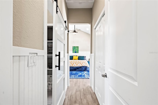 hallway featuring wood finished floors and a barn door