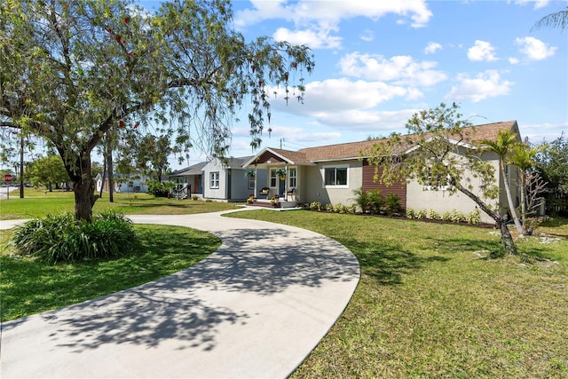ranch-style home with a front lawn, curved driveway, and stucco siding