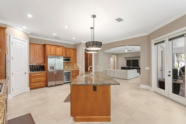 47 Martinique Ave, Tampa, FL 33606 - kitchen with stainless steel appliances, arched walkways, a sink, beverage cooler, and brown cabinetry