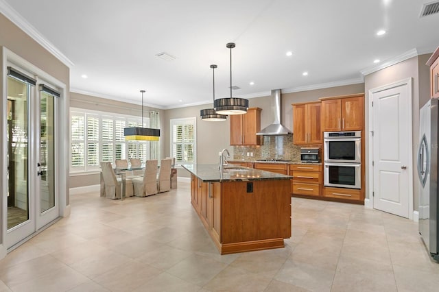47 Martinique Ave, Tampa, FL 33606 - kitchen with stainless steel appliances, decorative backsplash, a sink, brown cabinetry, and wall chimney exhaust hood