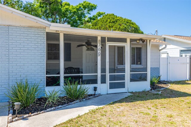 8766 91st St, Seminole, FL 33777 - entrance to property featuring brick siding, a yard, a ceiling fan, and fence