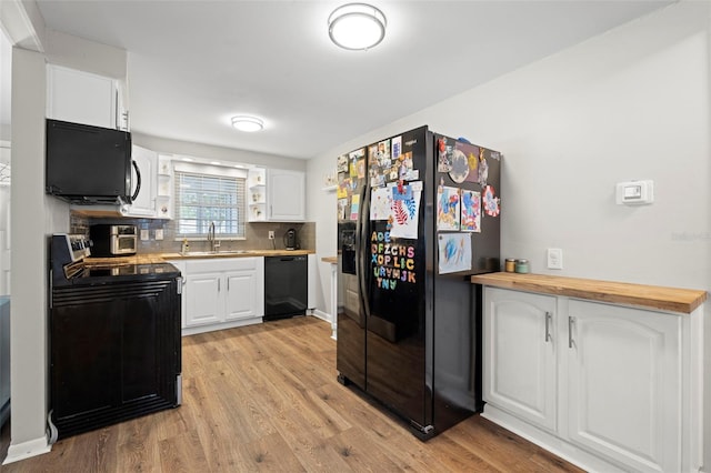8766 91st St, Seminole, FL 33777 - kitchen with white cabinets, light wood finished floors, backsplash, a sink, and black appliances